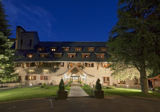 Parador de Arties in der Abenddämmerung, beleuchtete Fassade vor Bergkulisse